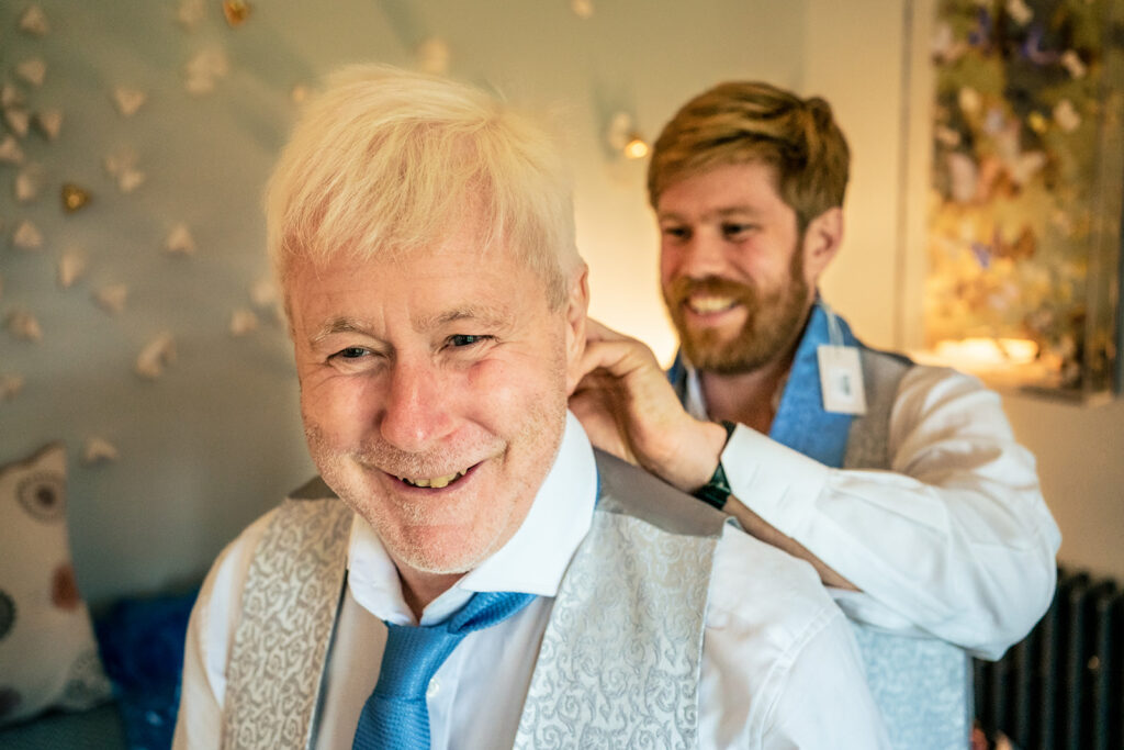 Guest laughing as his buttonhole goes on at Dorfold Hall, Cheshire