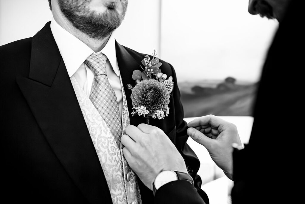 Groom fixing his cufflinks, black and white at Dorfold Hall, Cheshire