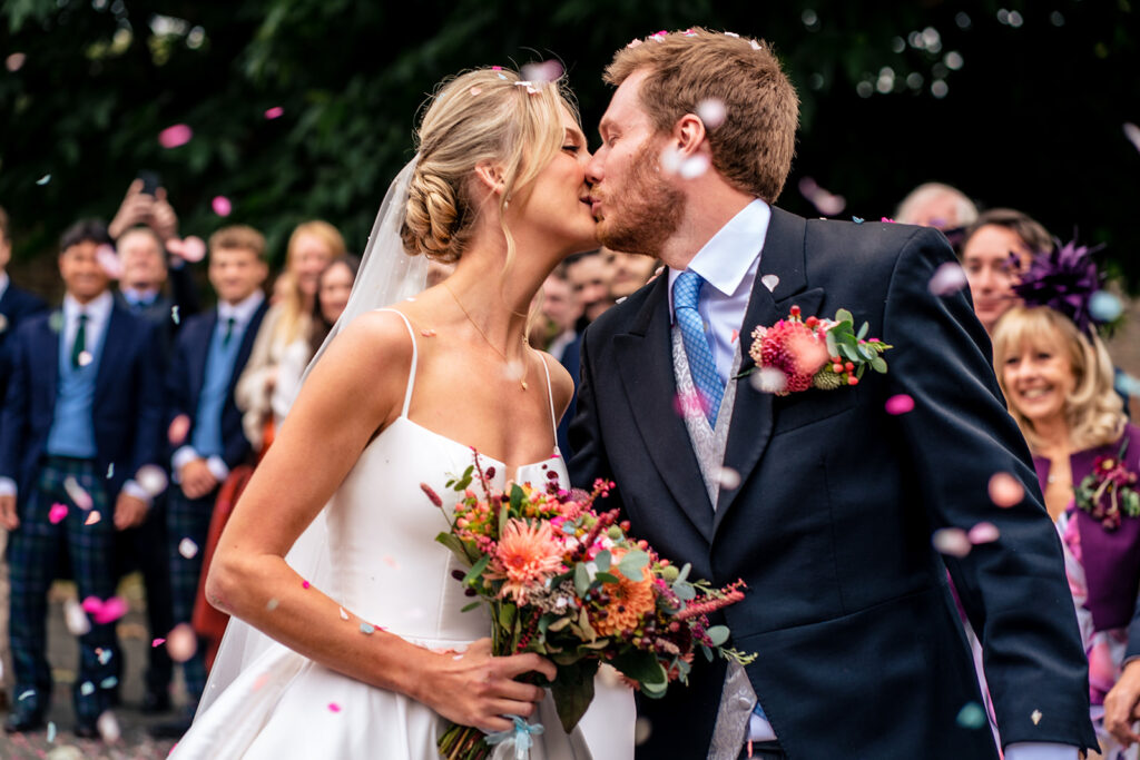 Just married kiss with guests cheering at Dorfold Hall, Cheshire
