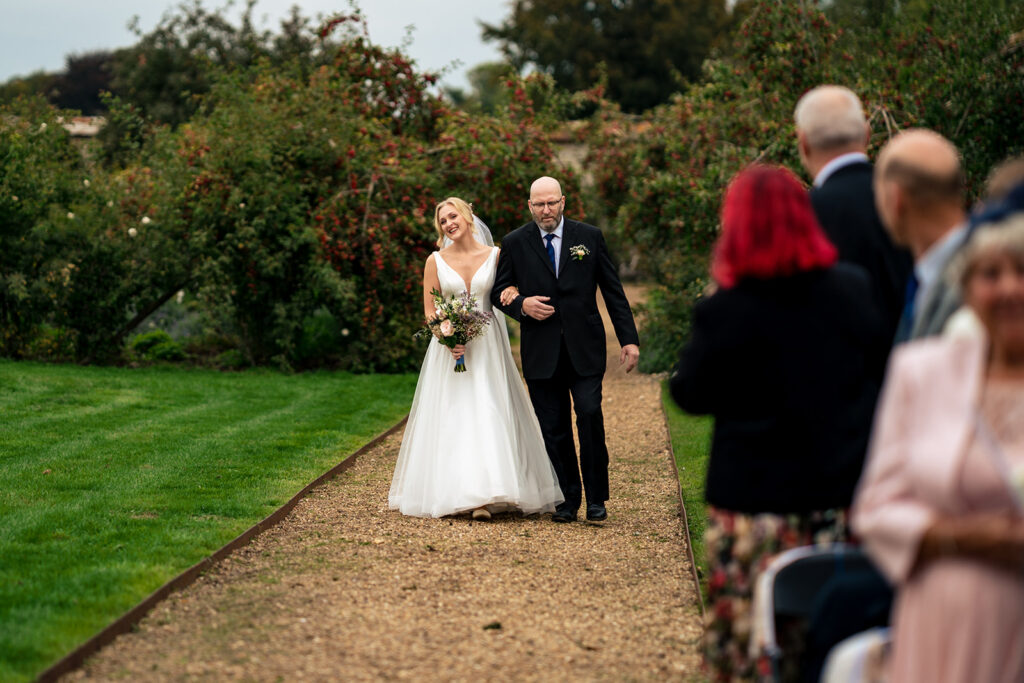 Bride walking down the garden aisle at Houghton Lodge Gardens, Hampshire