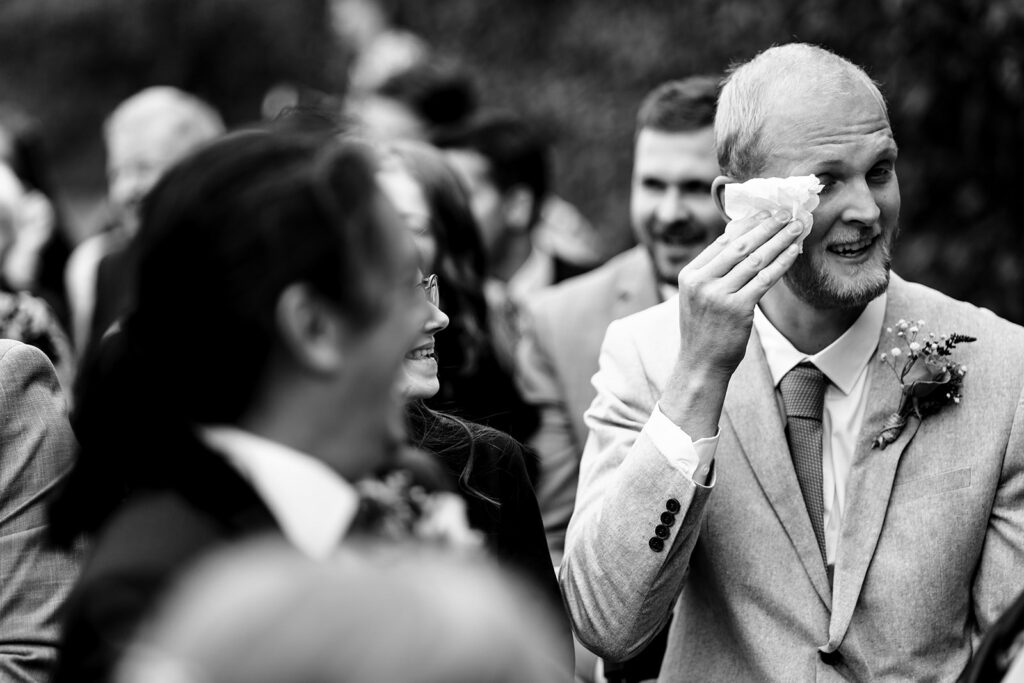 Groom wiping away a happy tear, black and white at Houghton Lodge Gardens, Hampshire