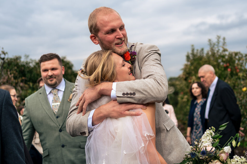 Groom getting a big hug from a guest at Houghton Lodge Gardens, Hampshire