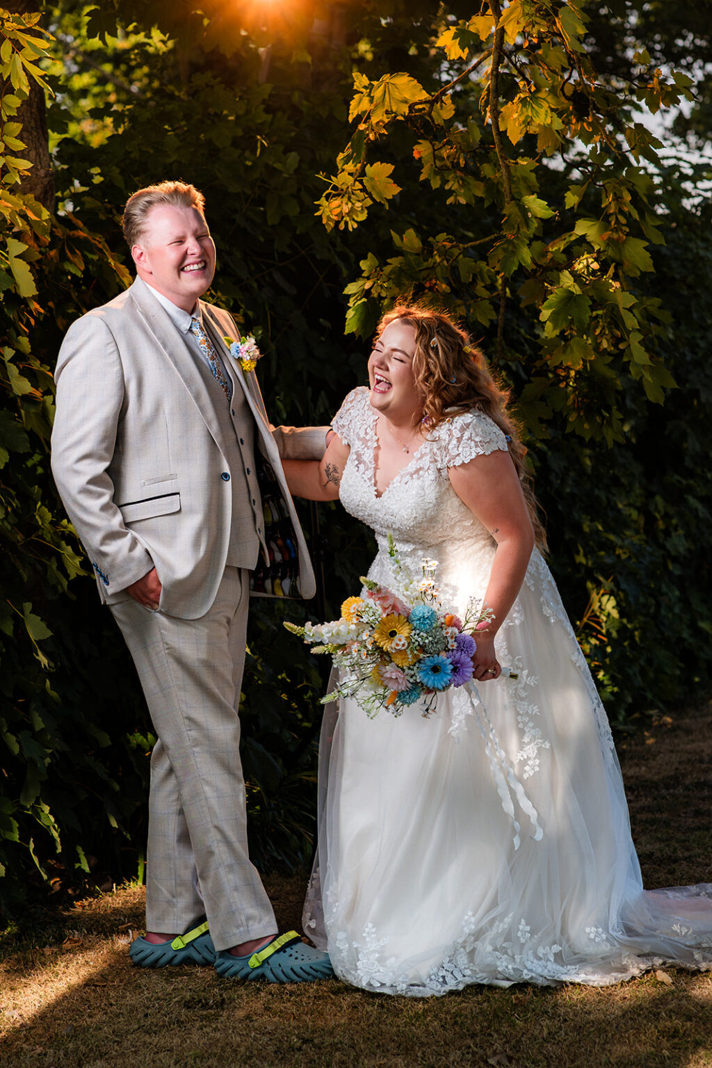 Bride and groom laughing in a fake golden sunset created with off camera flash in a car park