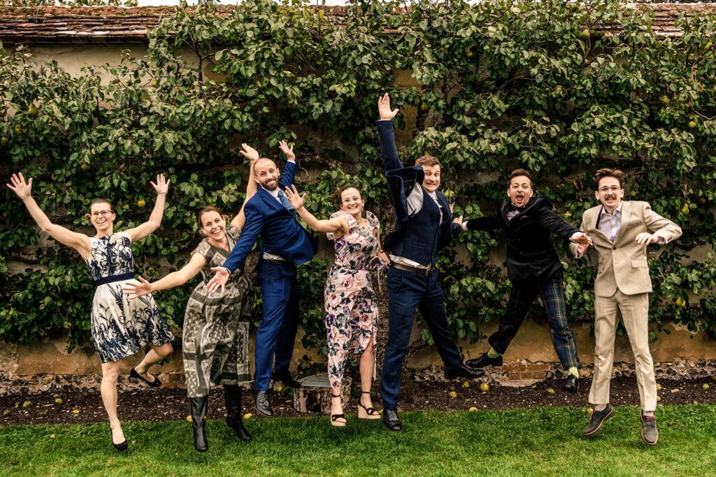 Wedding guests jumping in the air for a fun family formal at Houghton Lodge Gardens