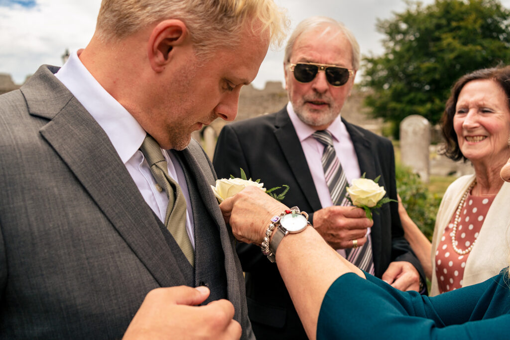Guests pinning on buttonholes before the ceremony at St Mary’s Church, Portchester