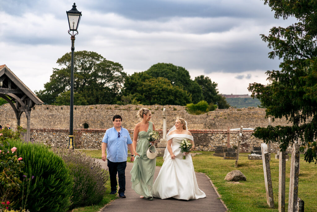 Bride walking up the church path with her bridesmaids at St Mary’s Church, Portchester