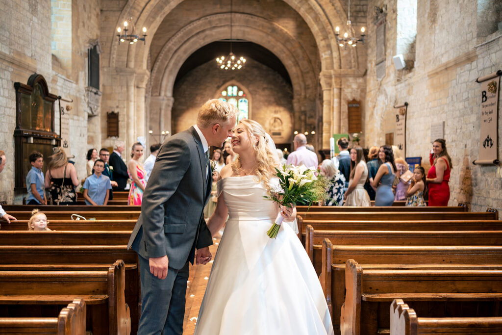 Just married kiss in the church aisle at St Mary’s Church, Portchester