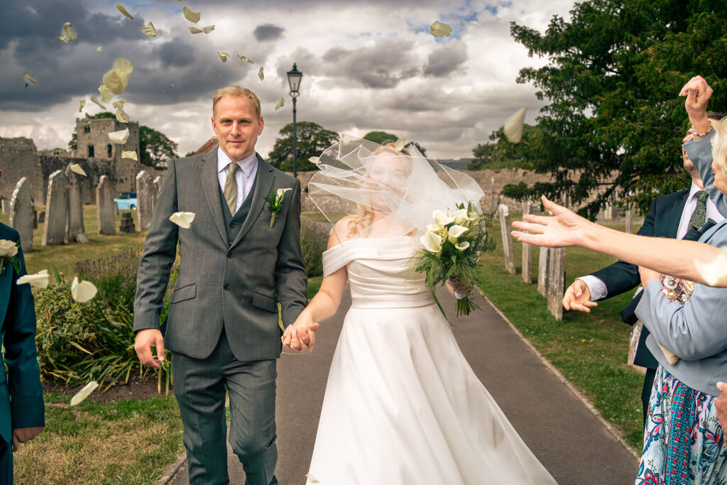 Bride and groom walking out arm in arm at St Mary’s Church, Portchester