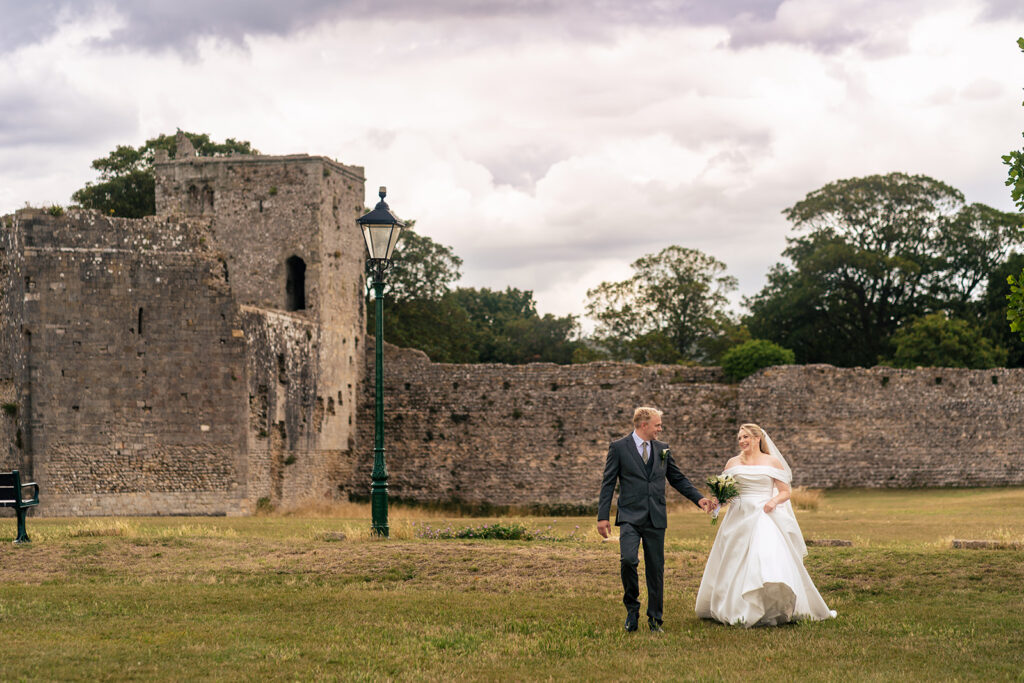 Couple walking by the castle walls at St Mary’s Church, Portchester
