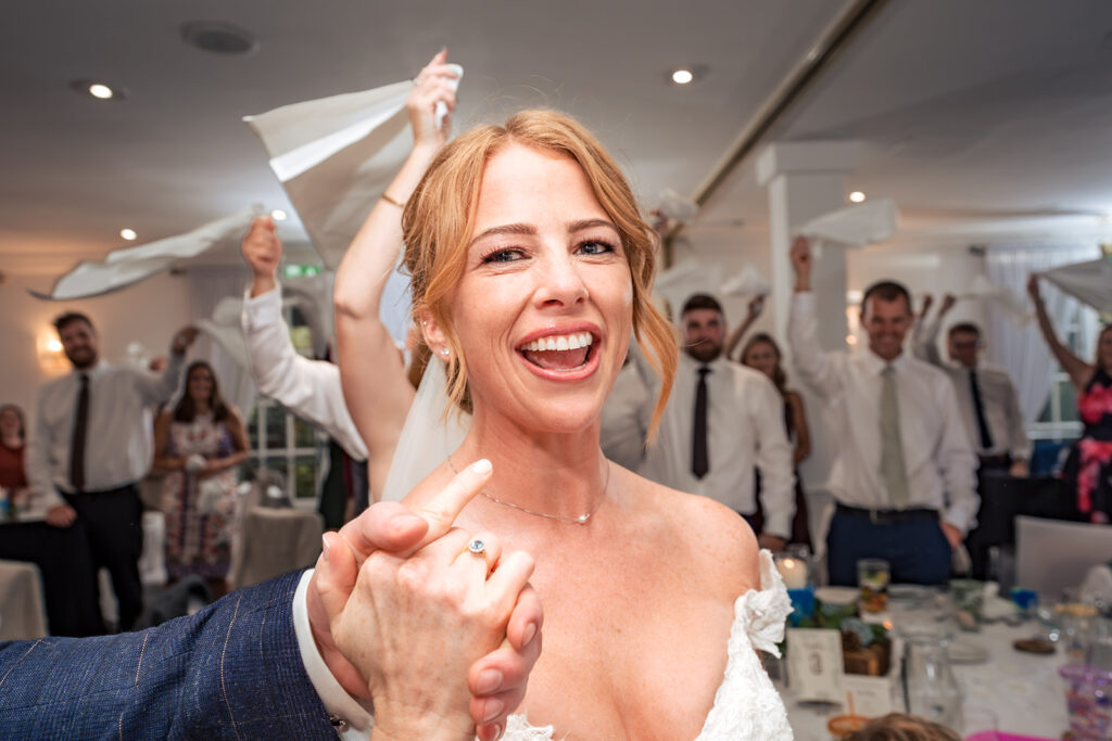 Bride laughing as guests wave napkins for the grand entrance to the wedding breakfast at Hotel Miramar Bournemouth