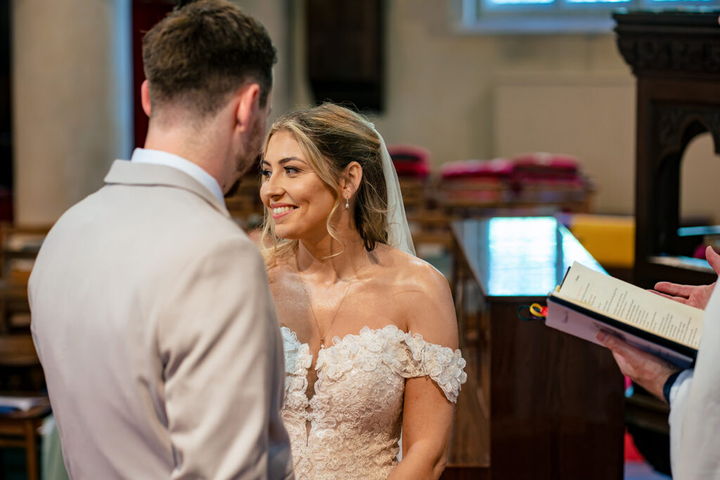 Jess and Luke smiling at each other during the ceremony at Newtown House Hotel, Hayling Island