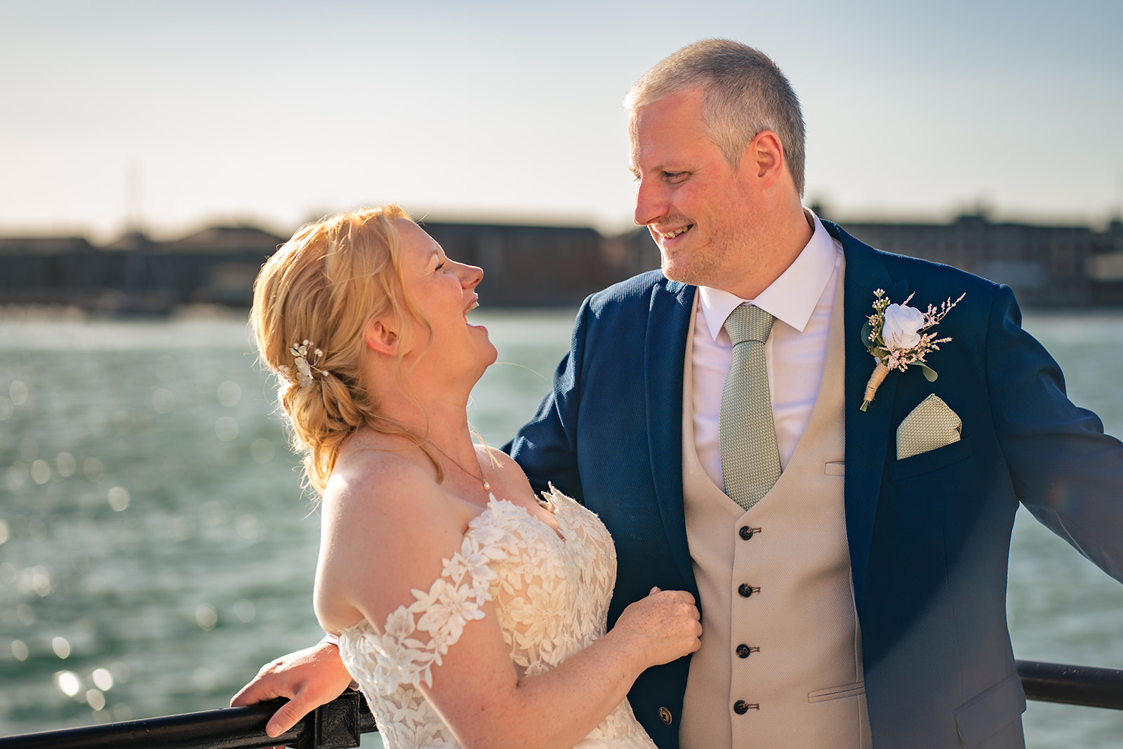 Groom smiling with his bride by the water in Old Portsmouth
