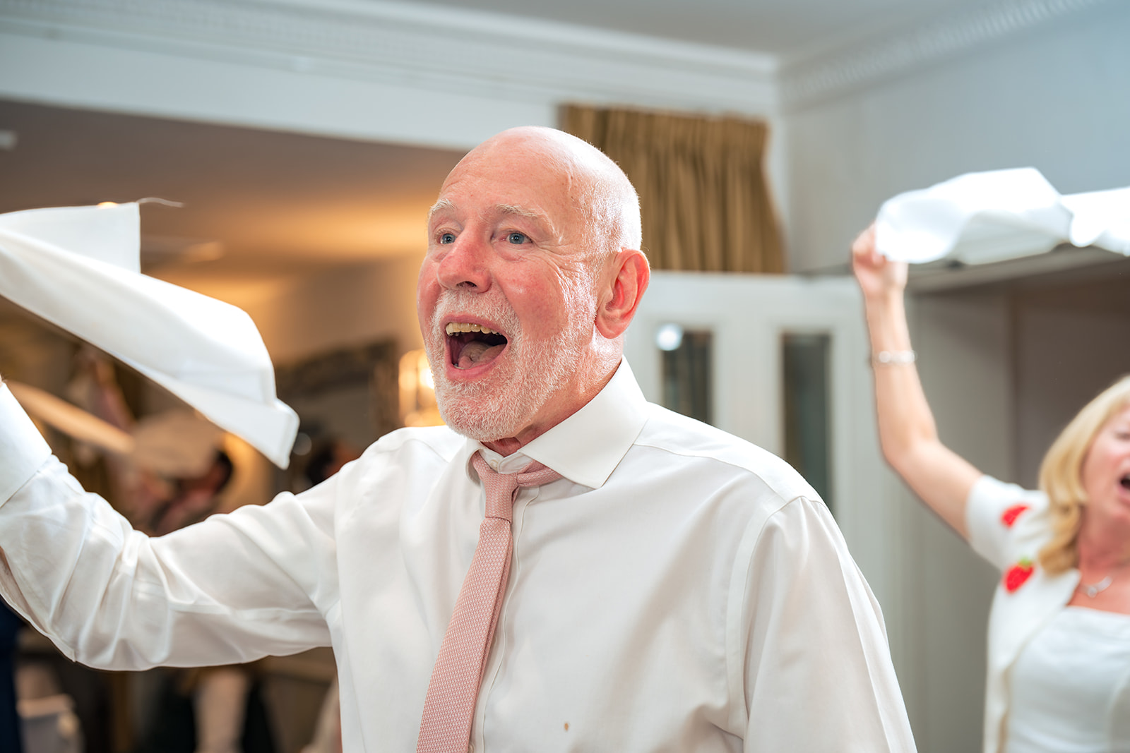 Older guest laughing and waving a napkin at the wedding breakfast at Hotel Miramar Bournemouth