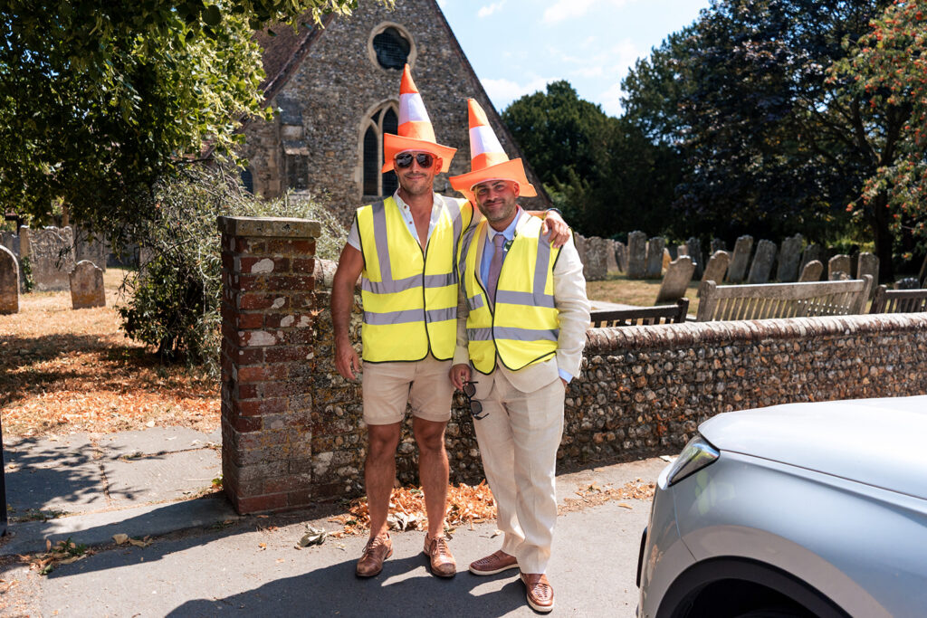 Guests in hi-vis jackets and traffic cone hats outside St Thomas à Becket Church, Warblington