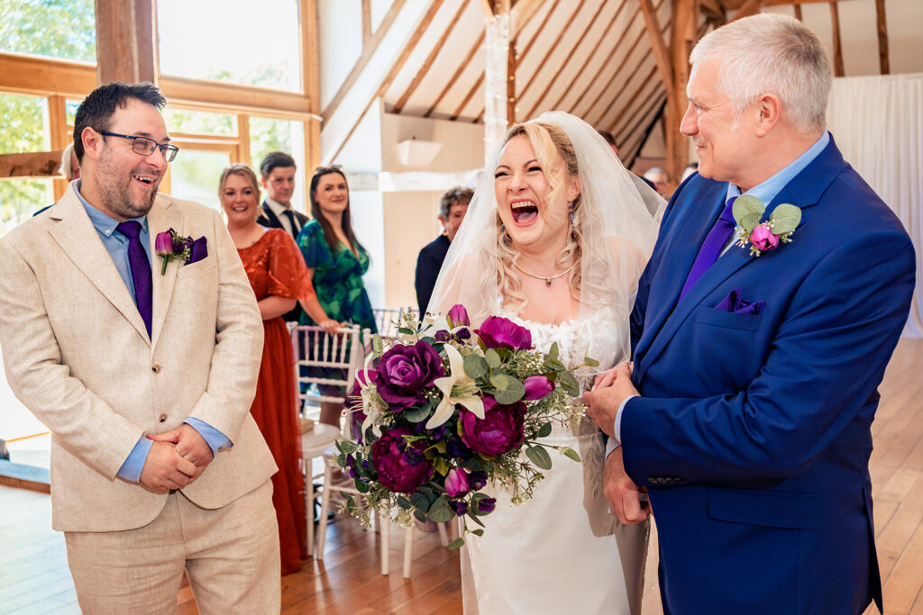 Bride laughing as she walks down the aisle with her dad at Skylark Golf and Country Club, Whiteley