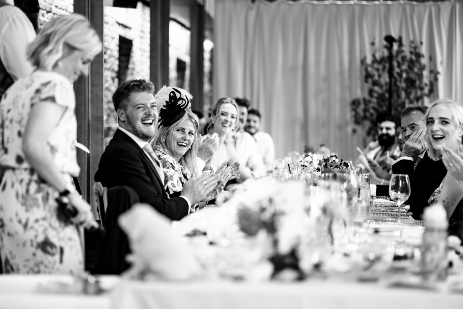 Guests in fits of laughter during the wedding speeches, black and white