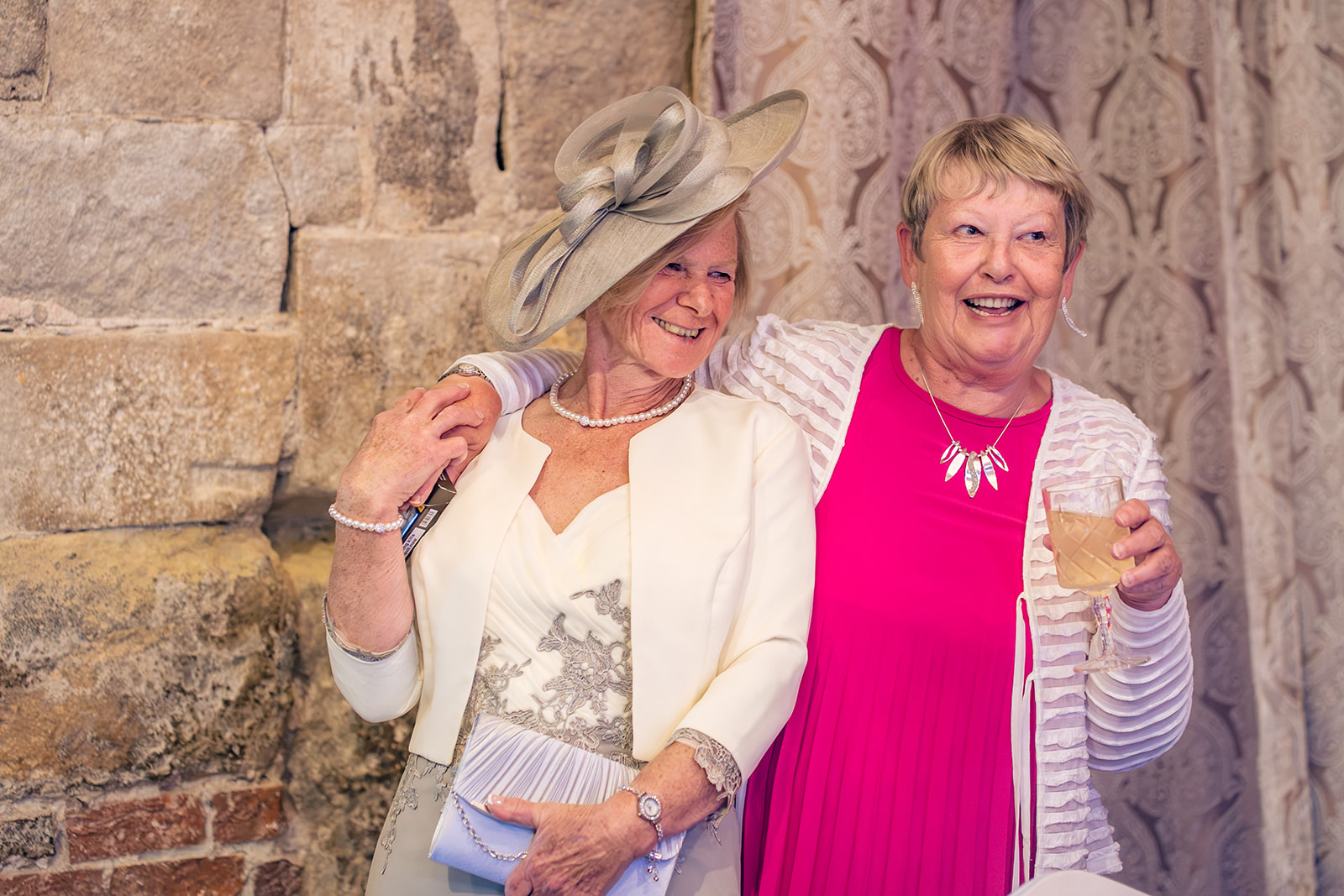 Two guests laughing together against the old stone walls of The Square Tower