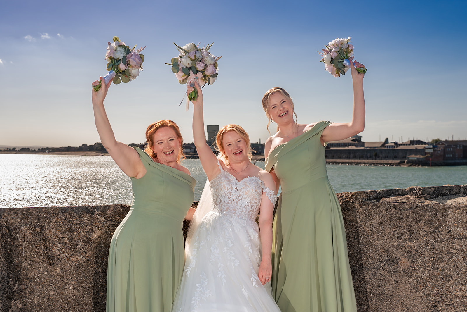 Bride and bridesmaids cheering with their bouquets on the rooftop of The Square Tower