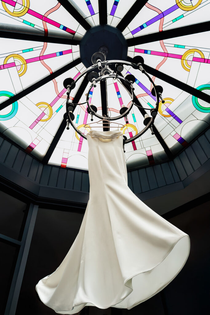 Wedding dress hanging in a round window at Ashbys and Southsea Castle, styled shoot