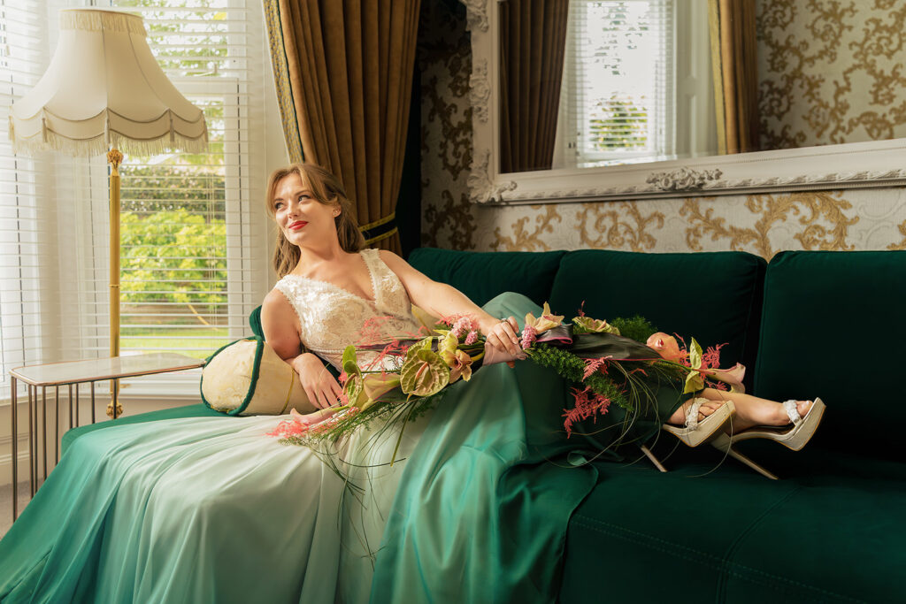 Bride lounging on a green velvet sofa at Ashbys and Southsea Castle, styled shoot