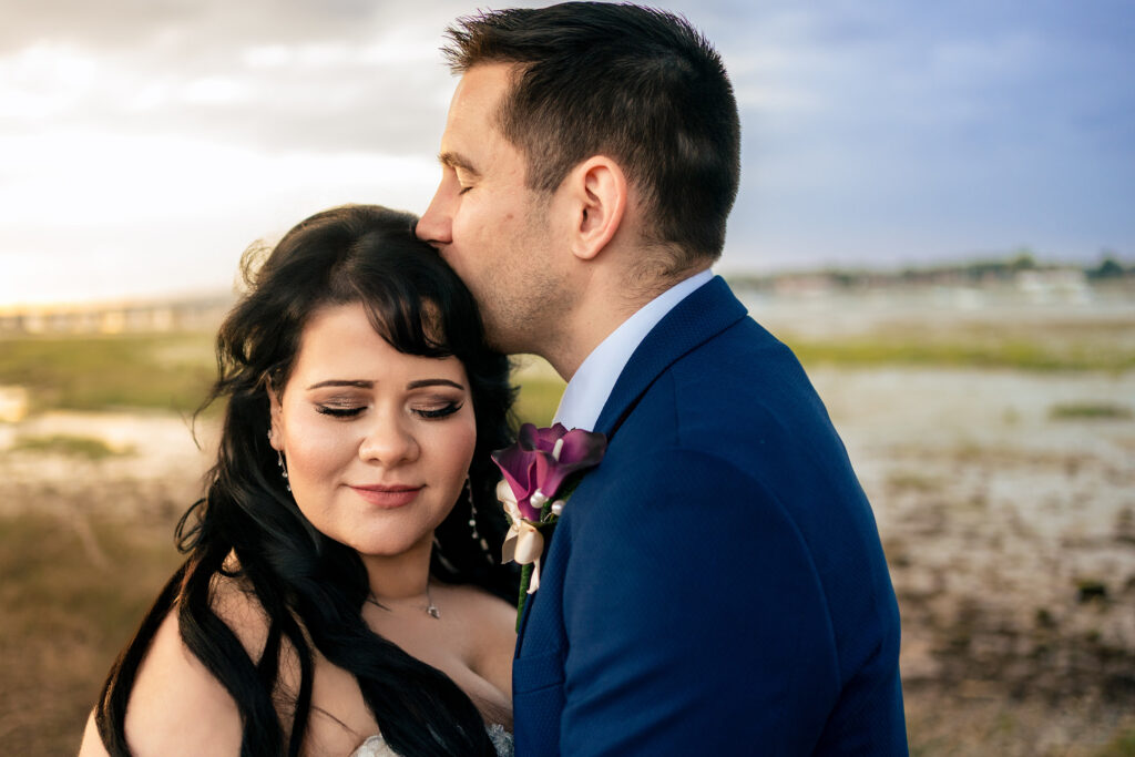 Groom kissing the bride’s forehead by the harbour at Langstone Quays Resort, Hayling Island