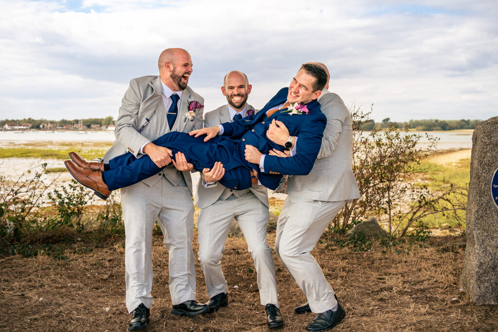 Groomsmen lifting the groom by the harbour at Langstone Quays Resort, Hayling Island