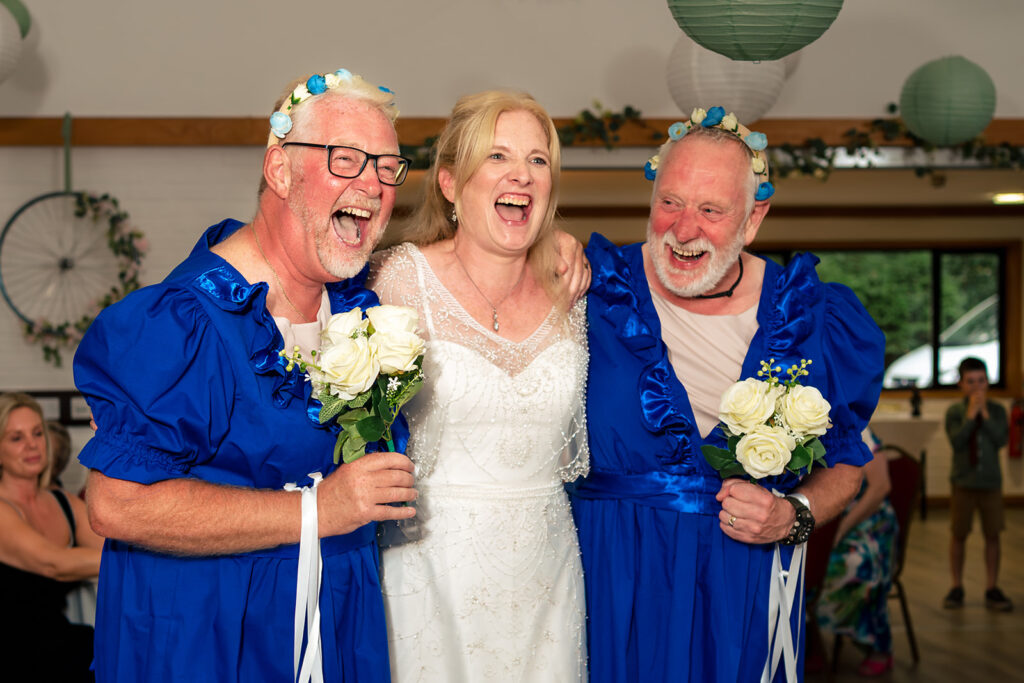 Bride laughing with guests in blue robes at Lodge Hill Centre, West Sussex