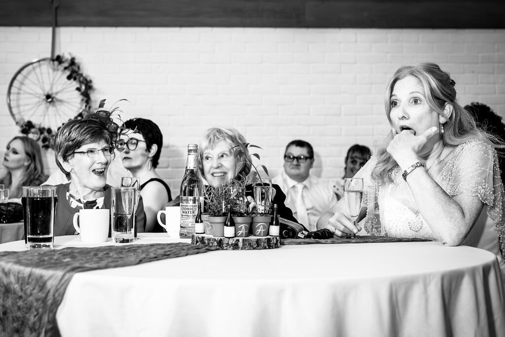 Bride laughing during the speeches, black and white at Lodge Hill Centre, West Sussex