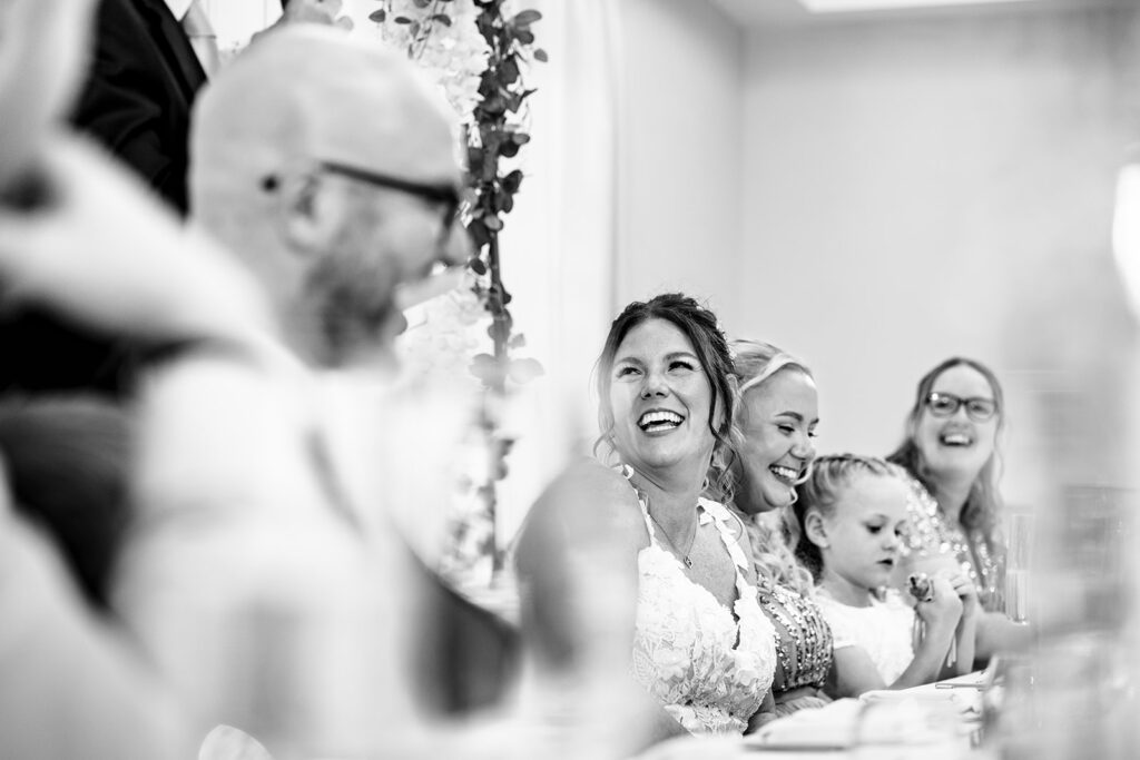 Bride laughing at the top table, black and white at Newtown House Hotel, Hayling Island