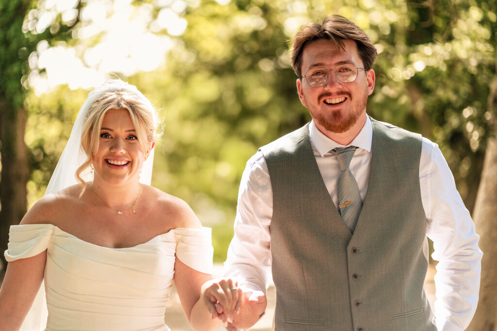 Bride and groom laughing hand in hand at Tournerbury Woods Estate, Hayling Island