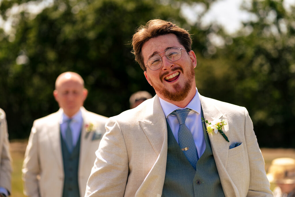 Groom grinning as he waits for the ceremony at Tournerbury Woods Estate, Hayling Island