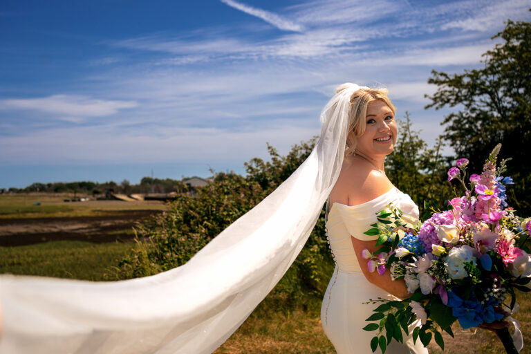 Bride with a long flowing veil in the meadow at Tournerbury Woods Estate, Hayling Island