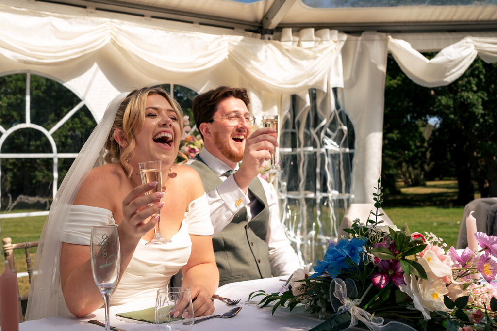 Bride and groom laughing at the top table at Tournerbury Woods Estate, Hayling Island